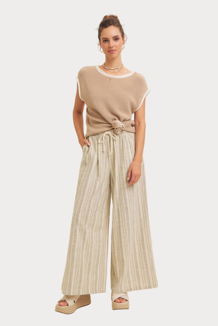A model wearing striped wide-leg pants with an elastic waistband and a beige top.