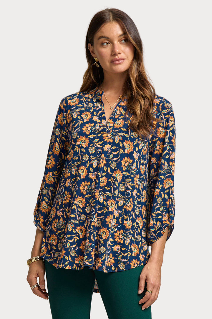 Woman wearing a floral blouse with a neutral background