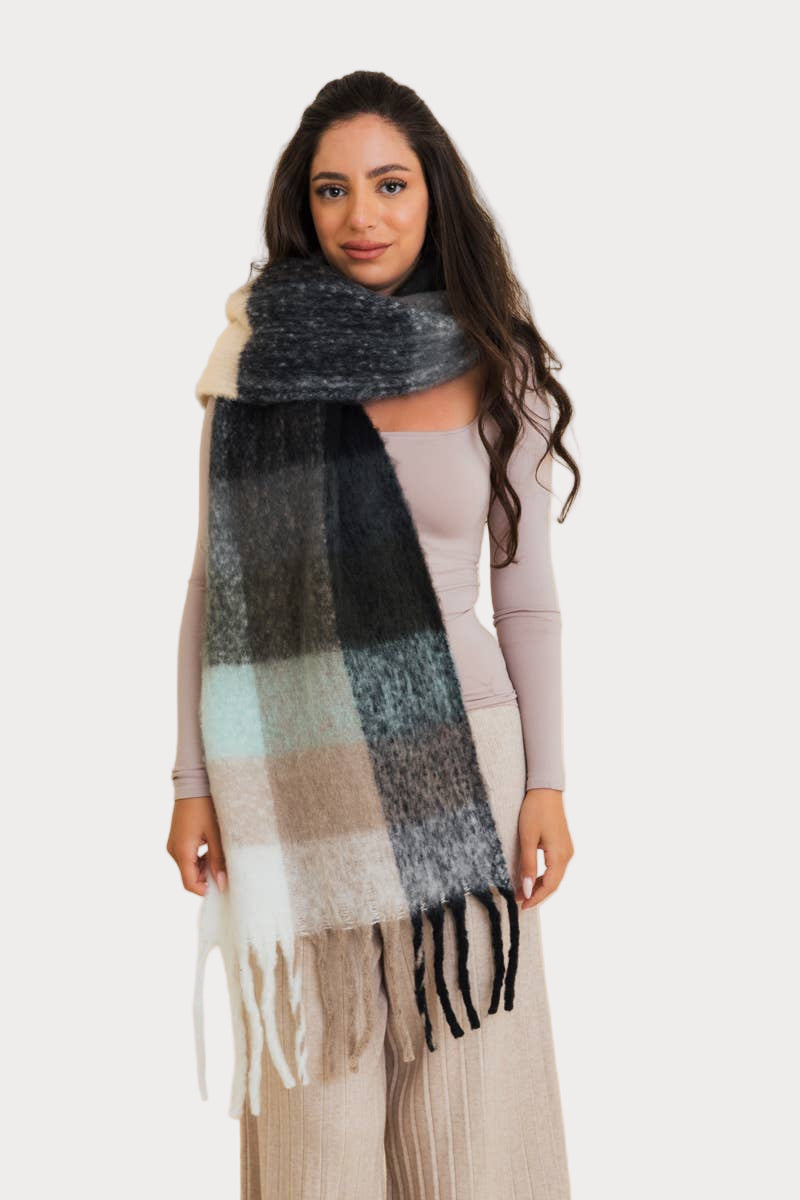 Woman wearing an oversized plaid scarf with fringe in soft neutral tones—cozy fall and winter accessory.