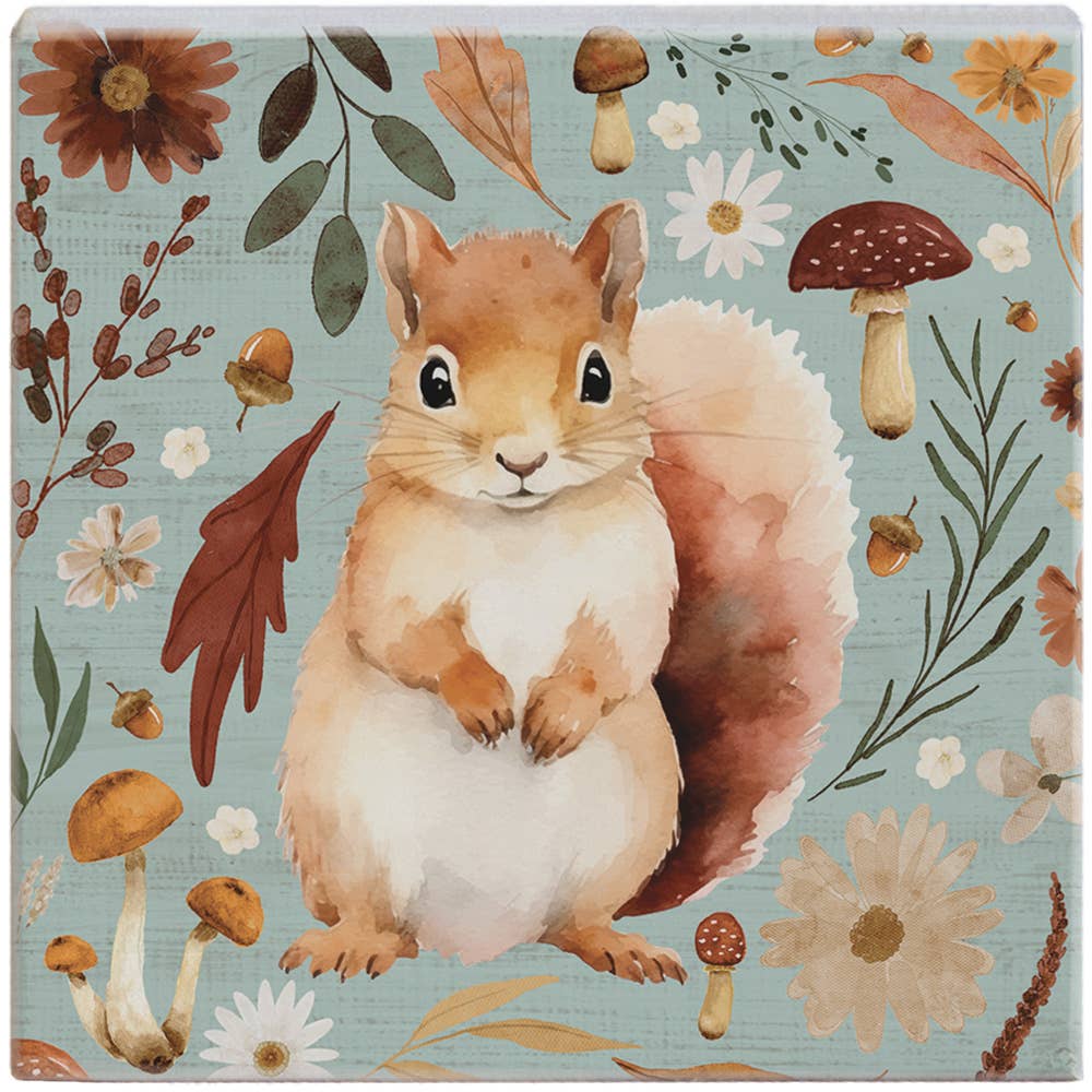 Wooden coaster with a squirrel design surrounded by flowers and leaves on a blue background