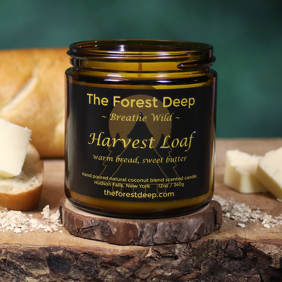 Jar of 'Harvest Loaf' candle from 'The Forest Deep' on a wooden surface with bread and butter.