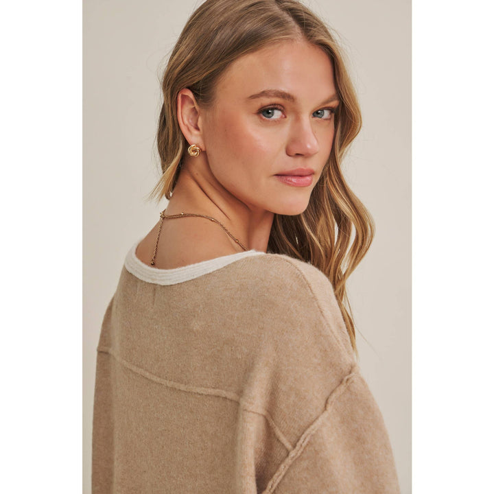 Woman wearing a beige sweater against a neutral background