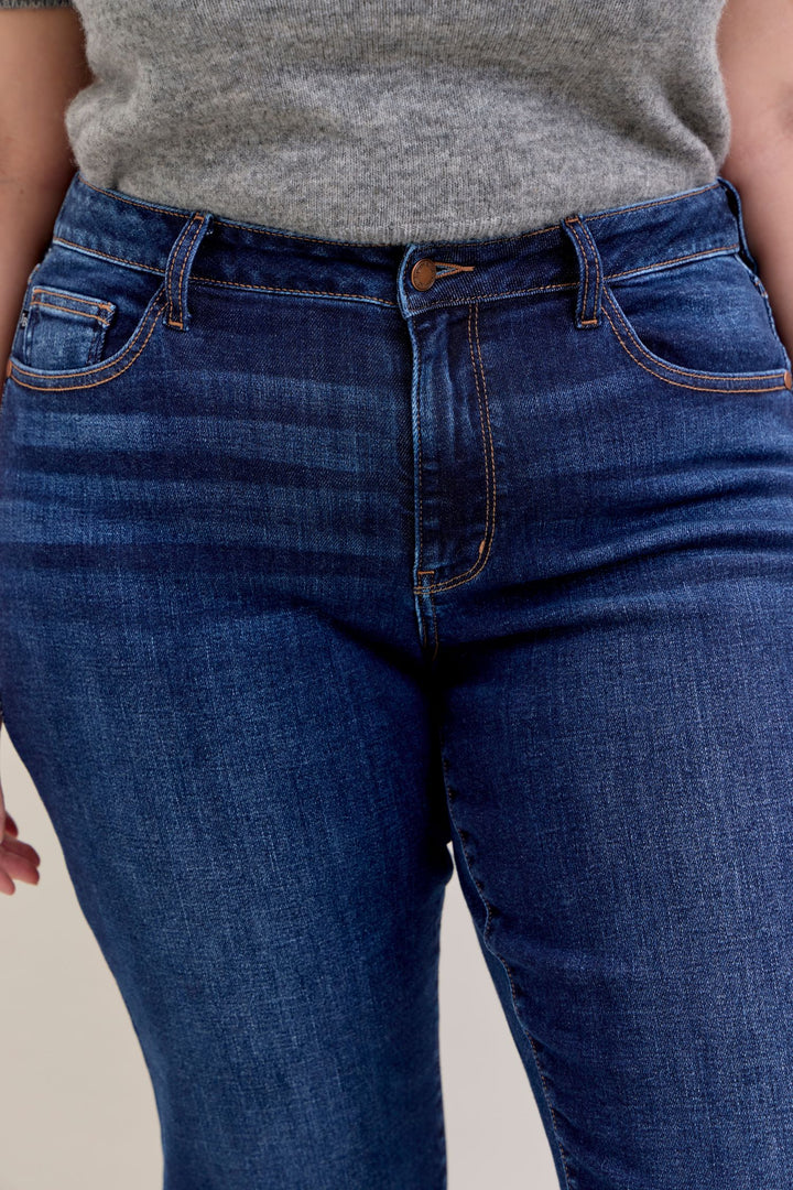 Model wearing Judy Blue mid-rise dark wash straight jeans with a short 30-inch inseam clode up front detail
