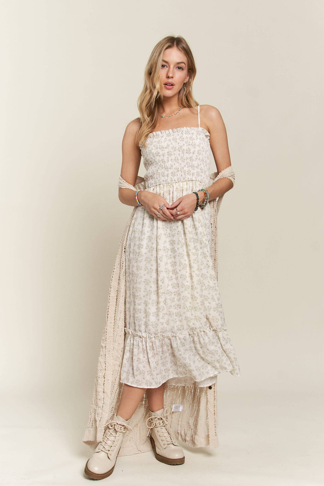 Woman wearing long beige crochet duster vest over a white floral dress