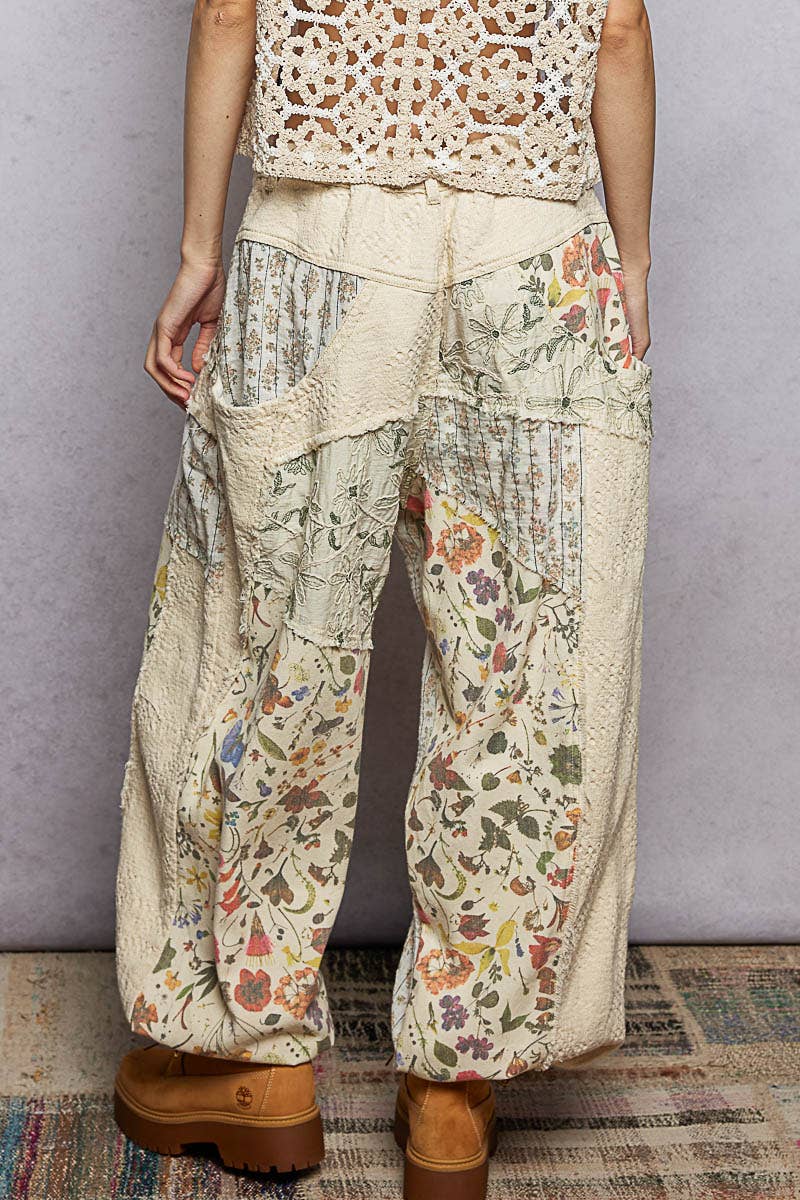 Model wearing The Cottage Bloom Patchwork Joggers by POL featuring vintage-inspired floral patchwork, textured jacquard details, oversized utility pockets, and a relaxed bohemian silhouette.