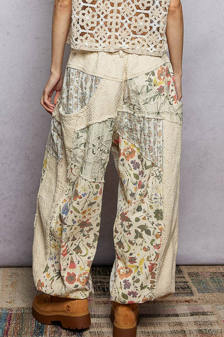 Model wearing The Cottage Bloom Patchwork Joggers by POL featuring vintage-inspired floral patchwork, textured jacquard details, oversized utility pockets, and a relaxed bohemian silhouette.