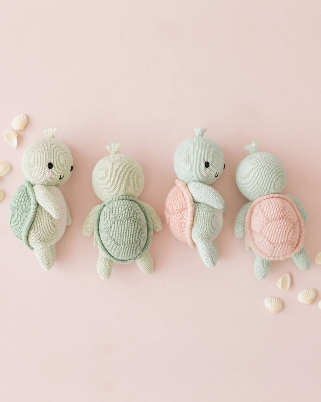 Four knitted turtle toys on a pink background