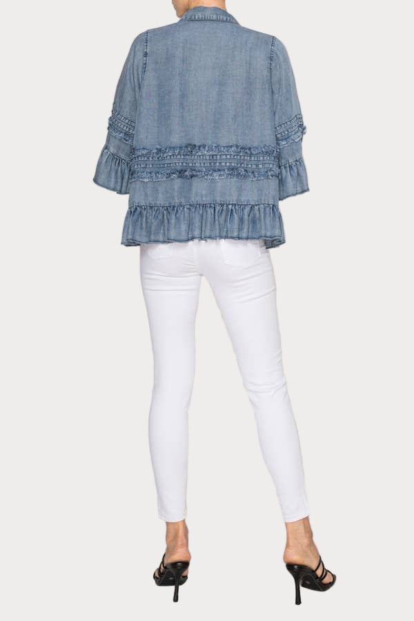 Denim top with ruffled details worn by a person on a white background