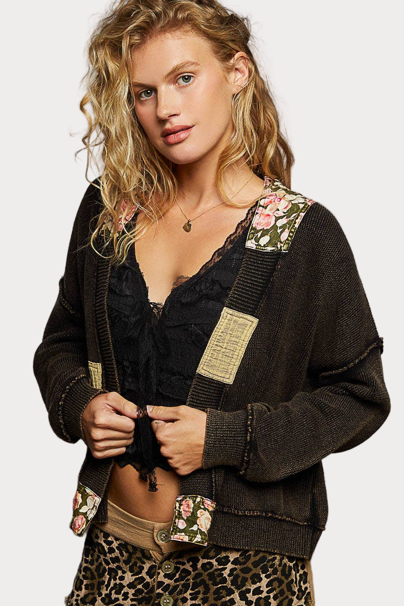 Woman wearing a patchwork knit open cardigan with floral trim, styled in a cozy boho look.