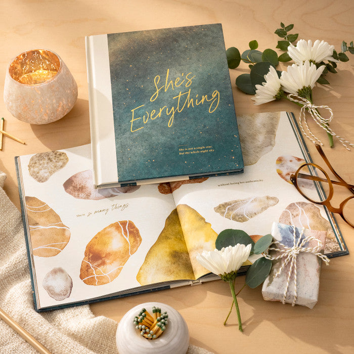 Two books on a surface with candles and flowers