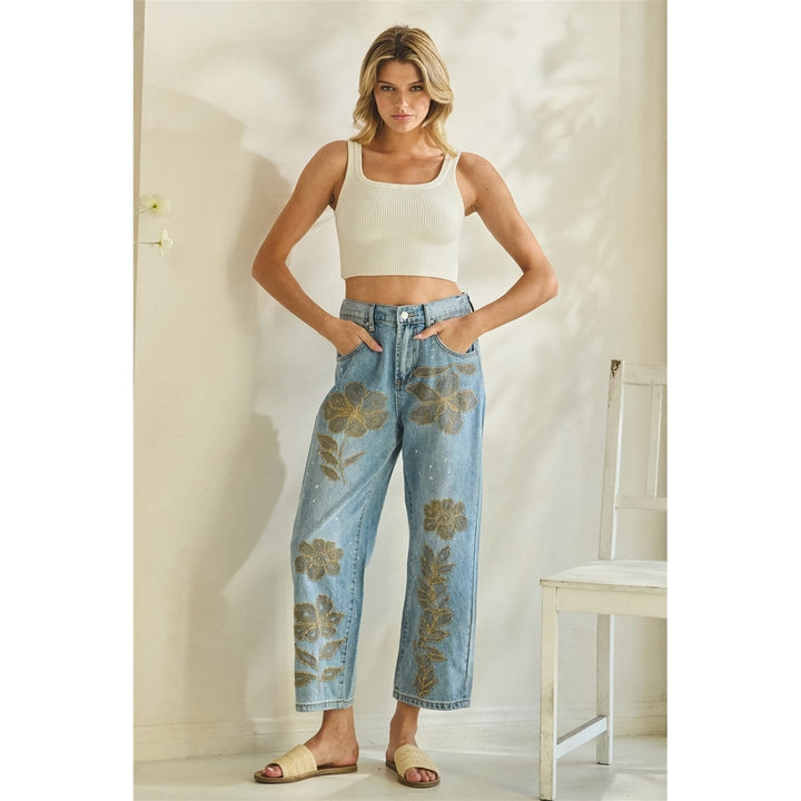Woman wearing a white tank top and floral jeans in a minimal indoor setting