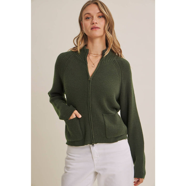 Woman wearing a green zip-up sweater against a plain background