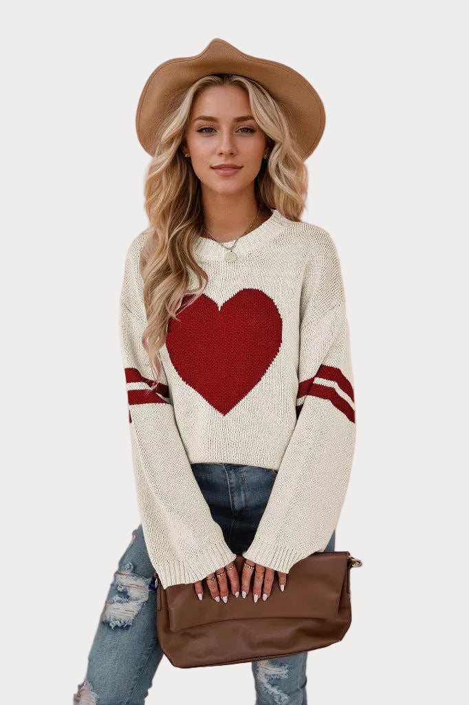 Women’s heart knit sweater pullover with cream base, red heart design, relaxed fit, and crew neckline styled with jeans