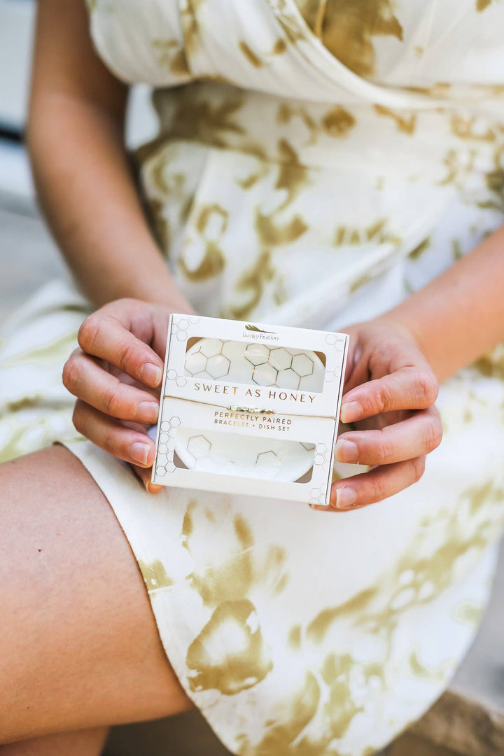 model holding Sweet as Honey bracelet and trinket dish gift set with white and gold honeycomb design