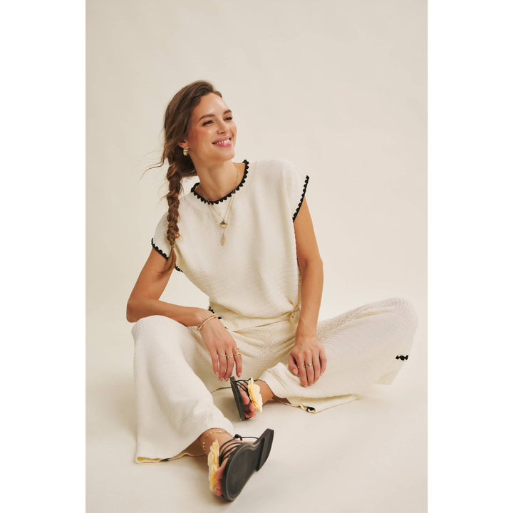 Cream textured sweater top with black whipstitch trim