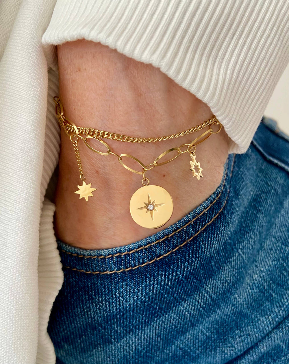 Gold layered bracelet with starburst, sun, and star charms. Shown on model