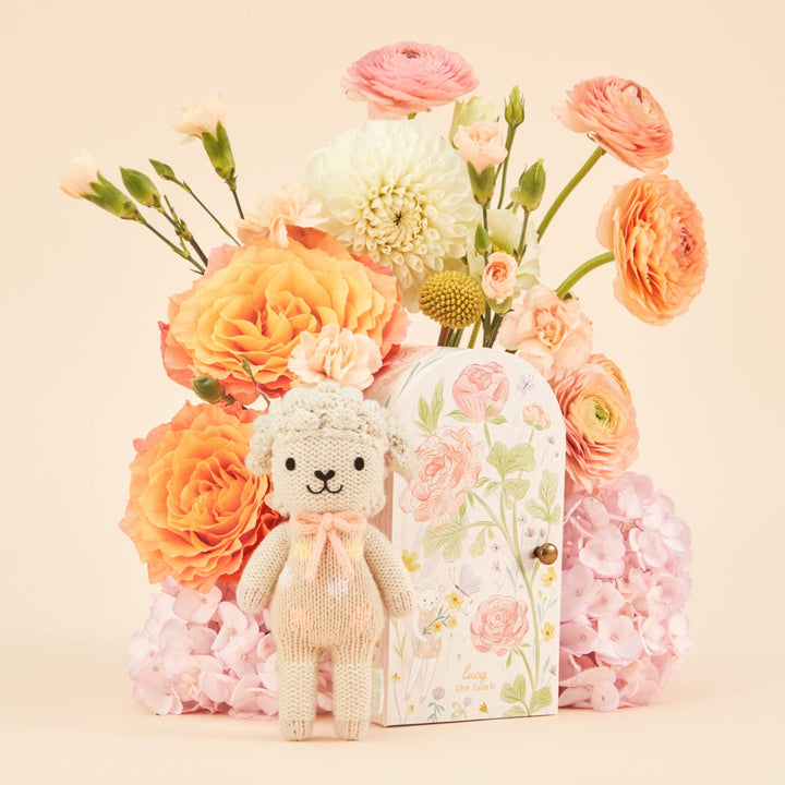 Knitted lamb with a floral gift box and bouquet of flowers on a beige background