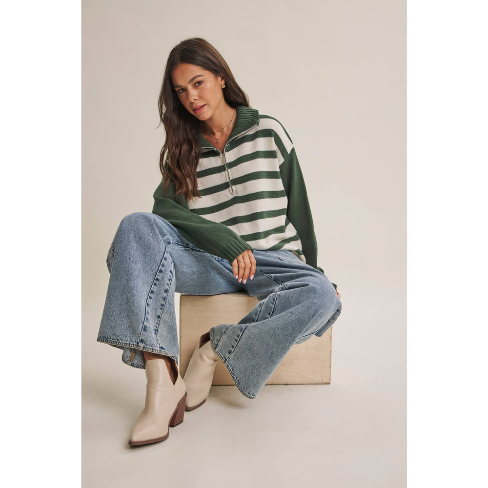 Woman wearing The Emerson evergreen and cream striped half-zip sweater with relaxed blue jeans