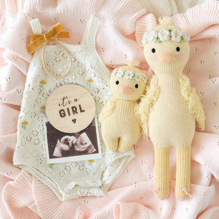 Baby girl outfit with knitted ducks on a pink textured background