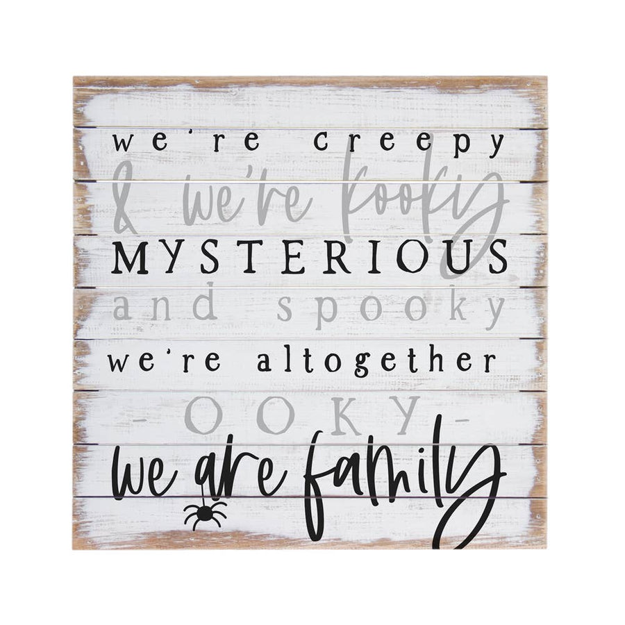Wooden sign with Halloween-themed Addams family theme song lyric text on a white background