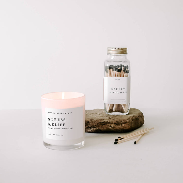 Candle labeled 'Stress Relief' with a jar of matches on a white background