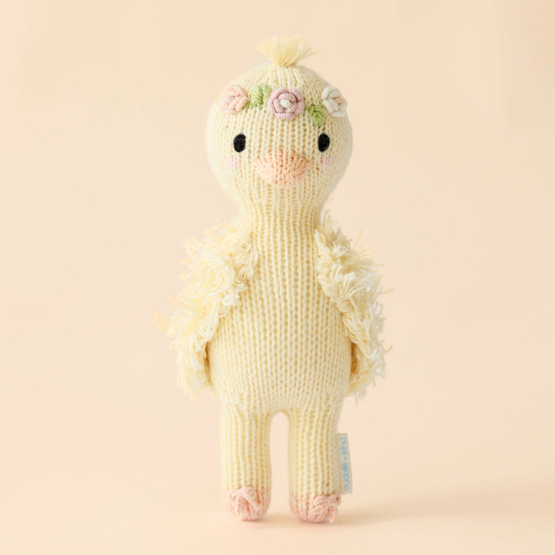 Knitted duck toy with floral details on a beige background