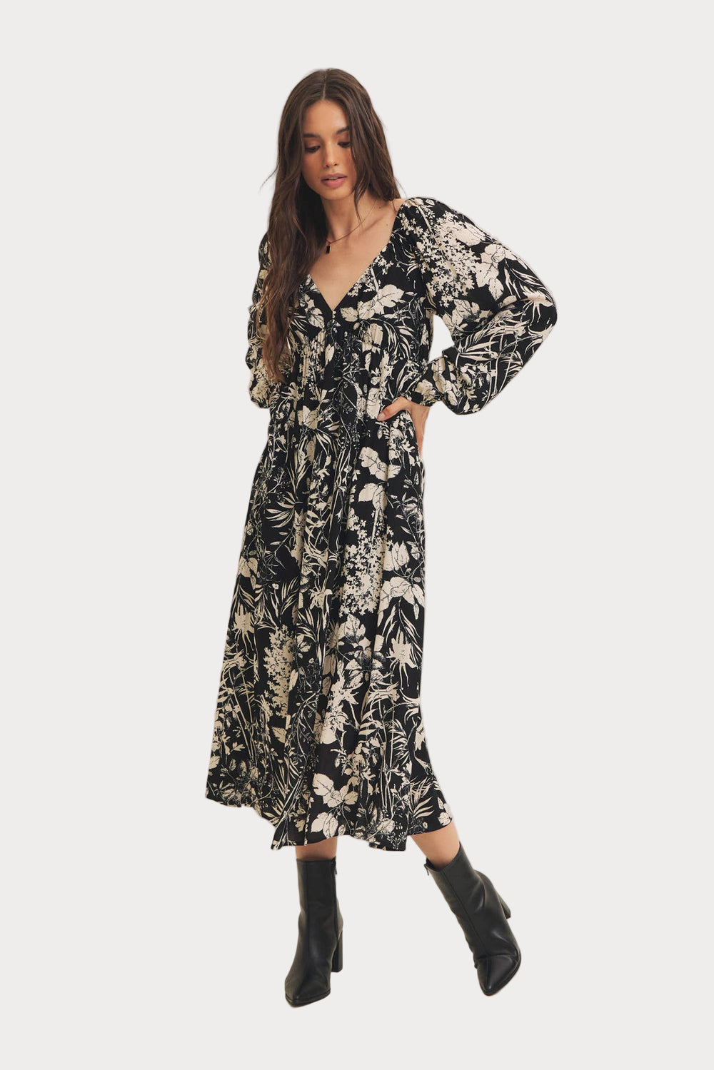 A woman wearing a black floral botanical print rayon midi dress with long sleeves, standing in a studio setting.