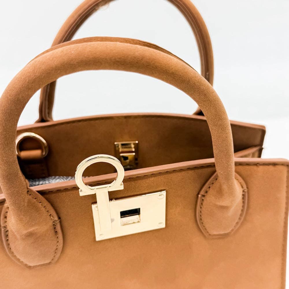 Close-up of a tan handbag with a gold clasp on a light gray background