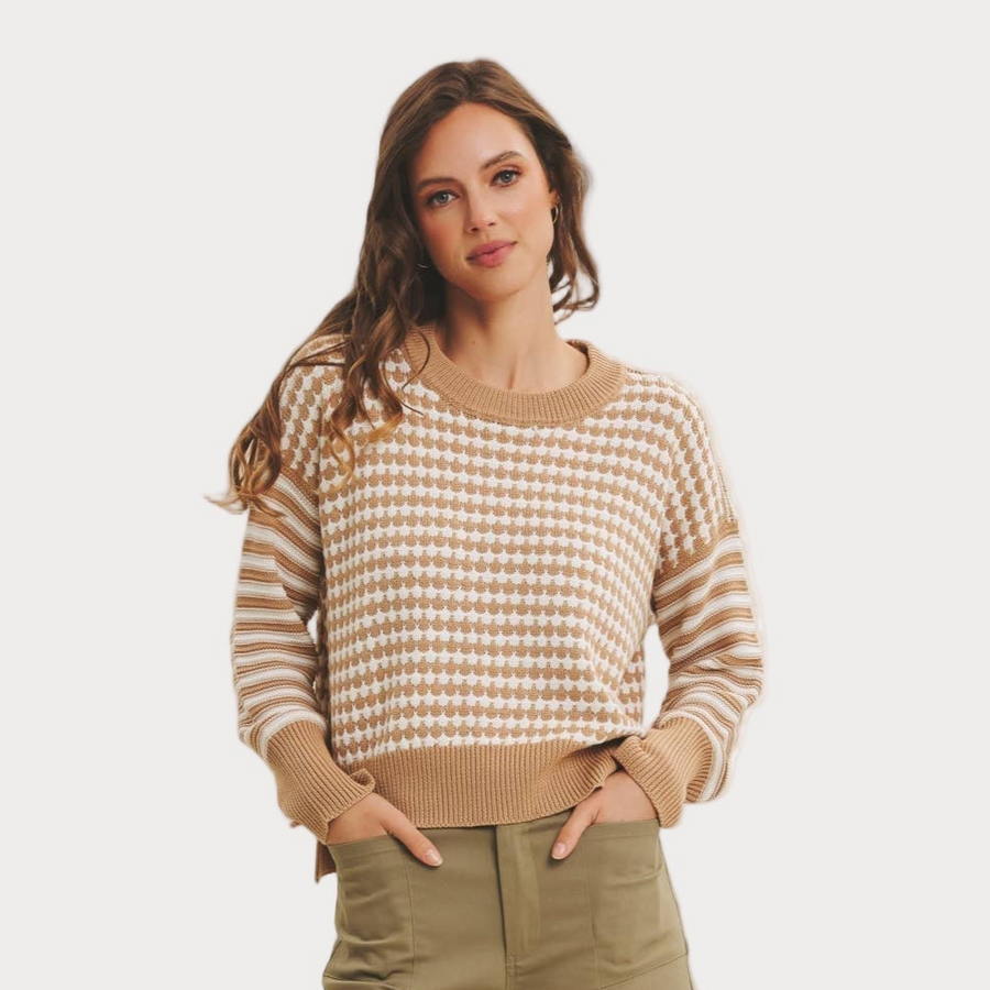 Woman wearing a beige and white patterned sweater on a plain background