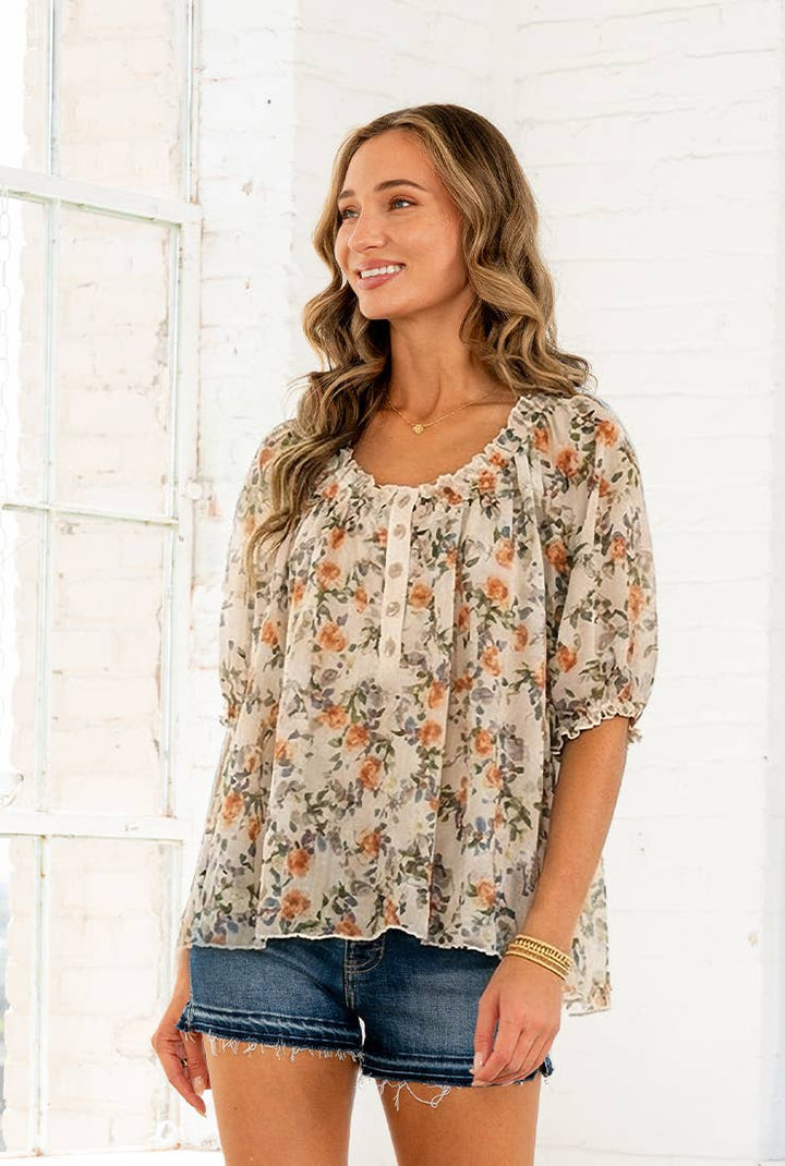Woman wearing lightweight floral blouse with ruffle neckline and short sleeves