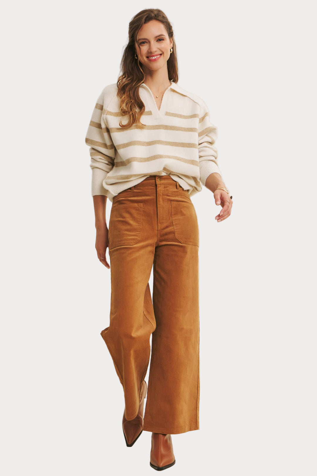 Woman wearing a striped shirt and brown pants on a plain background