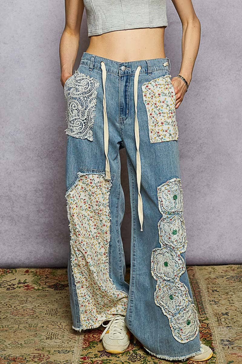 Blue denim pants with floral patchwork and lace details, wide-leg fit with drawstring waist.