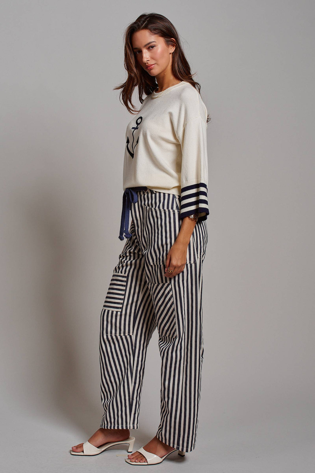 Woman wearing navy and ivory railroad stripe utility pants with oversized patch pockets, braided drawstring waist, and relaxed straight-leg fit.
