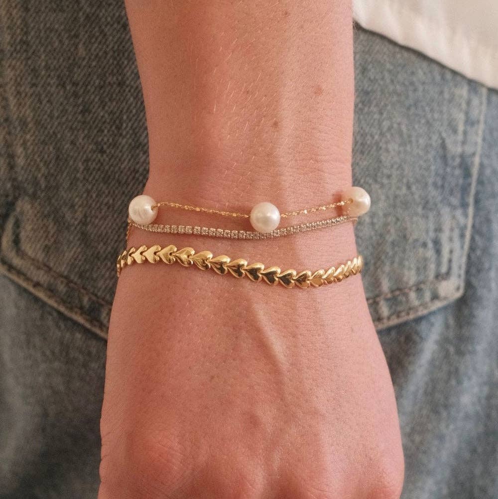 gold bracelet with floating freshwater pearls on delicate chain shown on model stacked with other bracelets