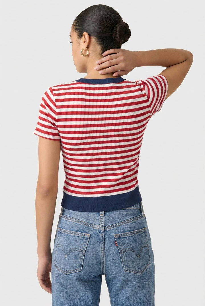 Woman wearing a red, white striped cardigan with navy trim on a white background, back view