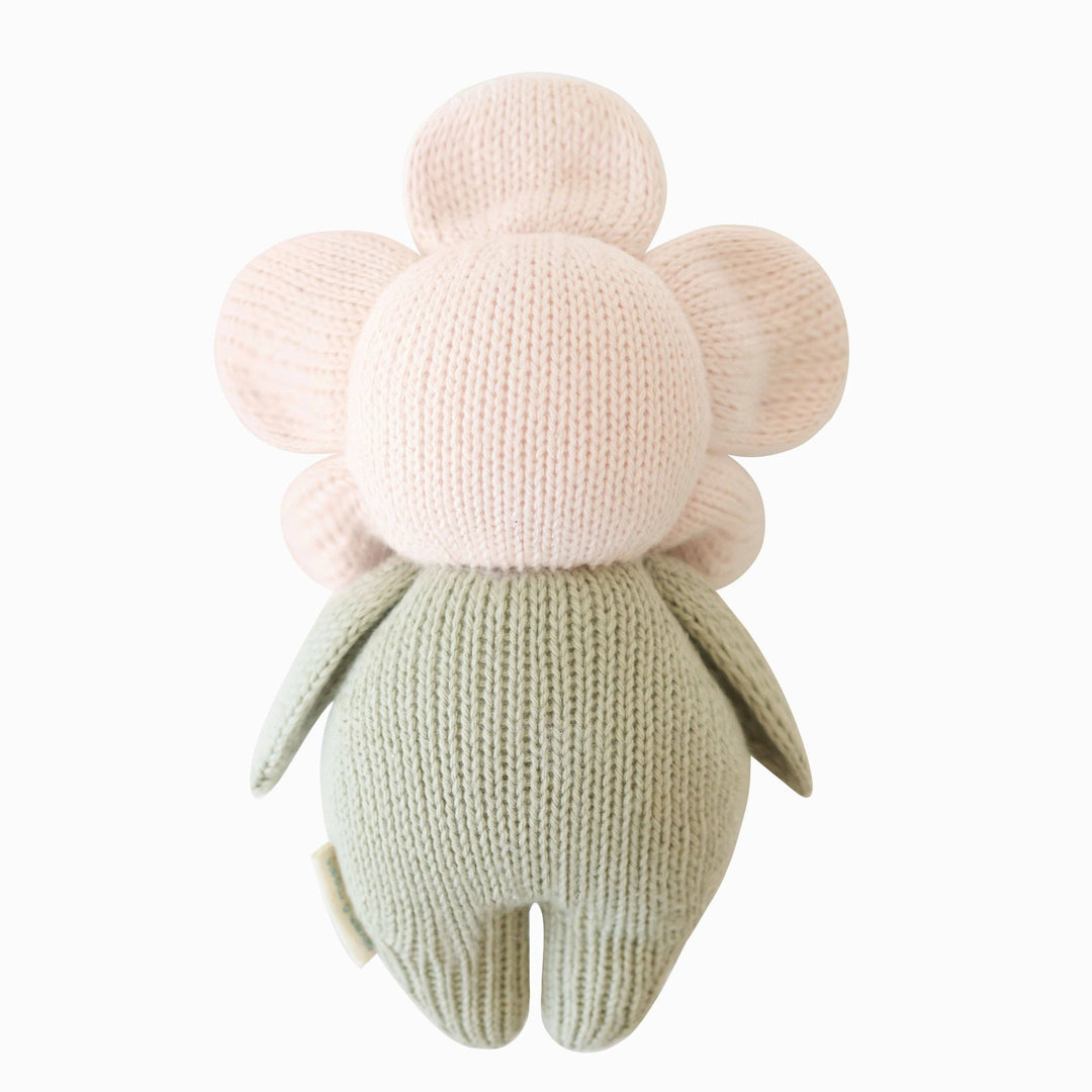 Knitted toy shaped flower with a pale pink center and green leaves on a white background