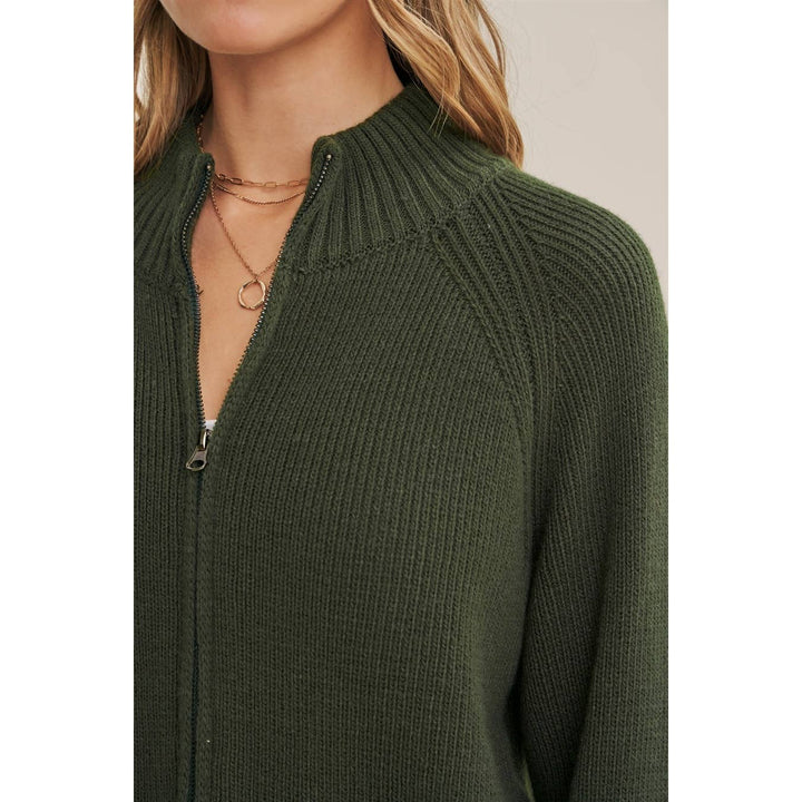 Green ribbed sweater with a zipper detail on a plain background