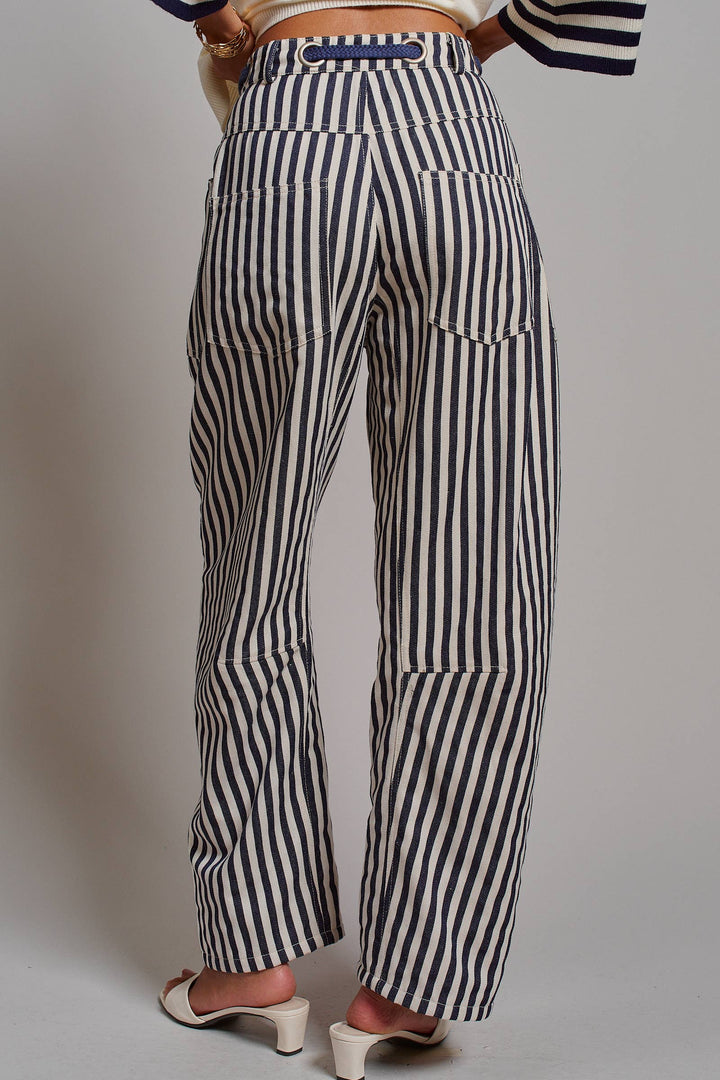 Woman wearing navy and ivory railroad stripe utility pants with oversized patch pockets, braided drawstring waist, and relaxed straight-leg fit.