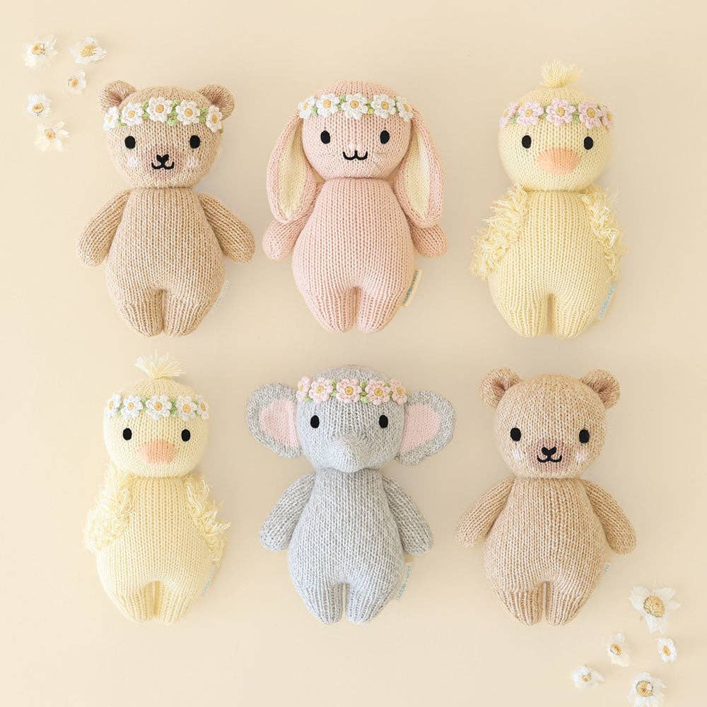 Set of six knitted toys in various colors with flower crowns on a beige background