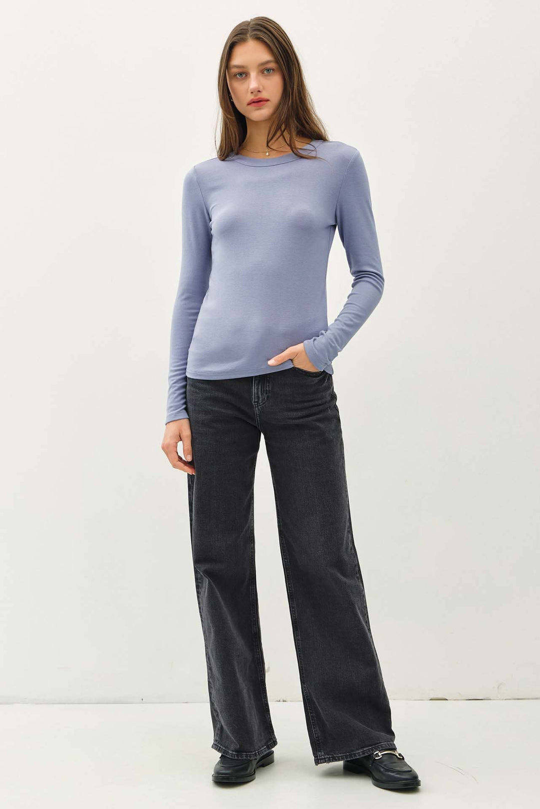 Woman wearing a light blue sweater and black pants on a white background
