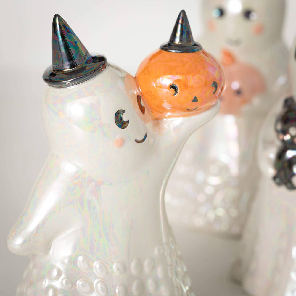 Halloween-themed ceramic figures with ghost, pumpkin, and witch hat designs on a white background.