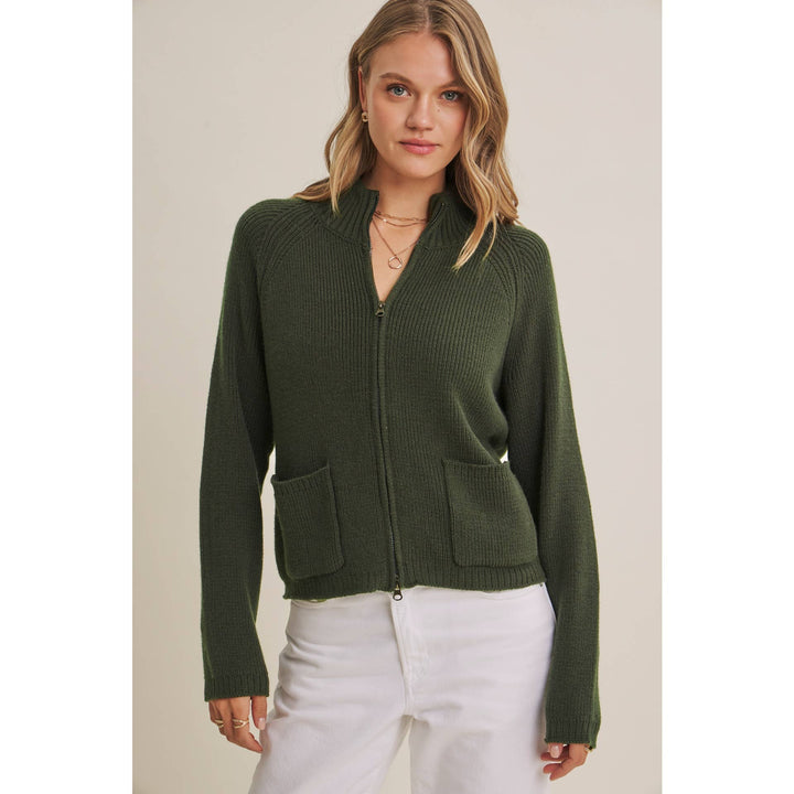 Woman wearing a green zip-up sweater against a beige background