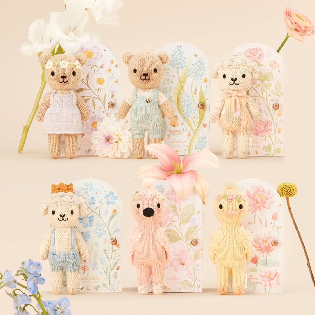 Set of small knitted animals with their keepsake boxes in pastel colors with floral backdrops on a light background