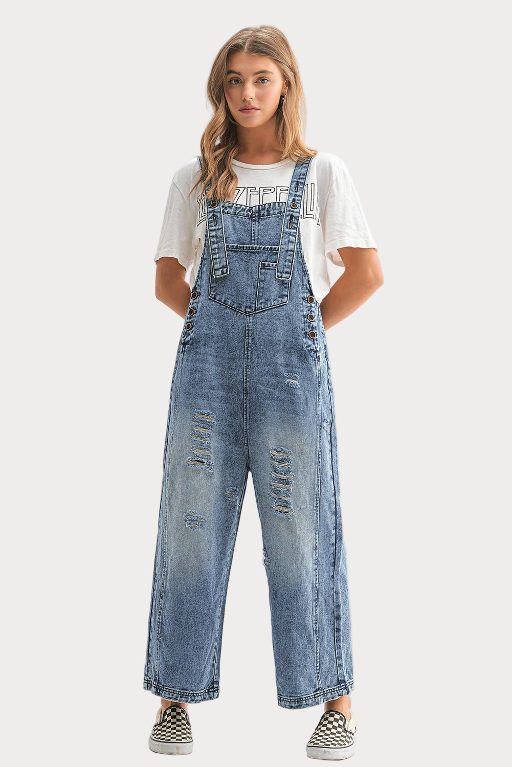 Woman wearing a pair of blue denim overalls on a white background