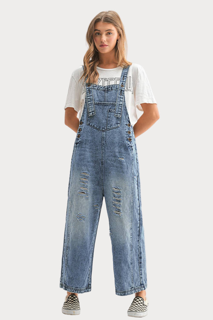 Woman wearing a pair of blue denim overalls on a white background