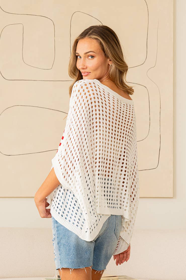 Woman wearing white open-knit sweater top with American flag design and denim jeans