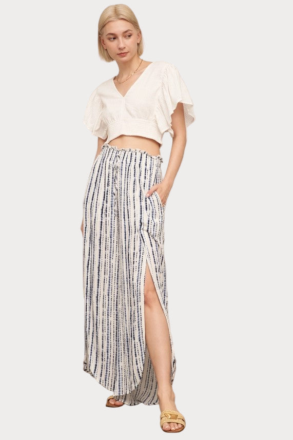 A model wearing front slit striped pants paired with a white top and sandals.