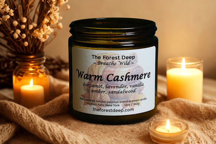 Candle jar labeled 'Warm Cashmere' with candles and dried flowers in the background