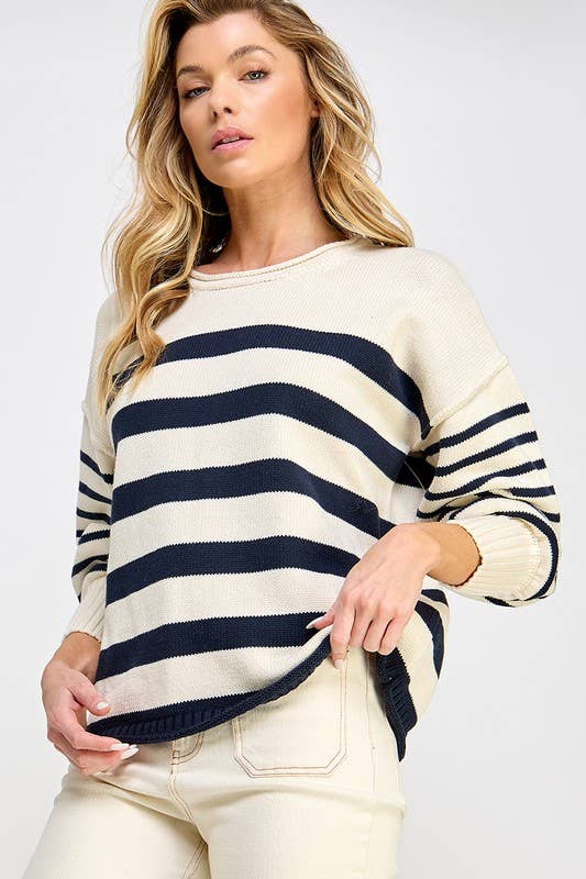 Woman wearing a cream and navy striped sweater on a white background