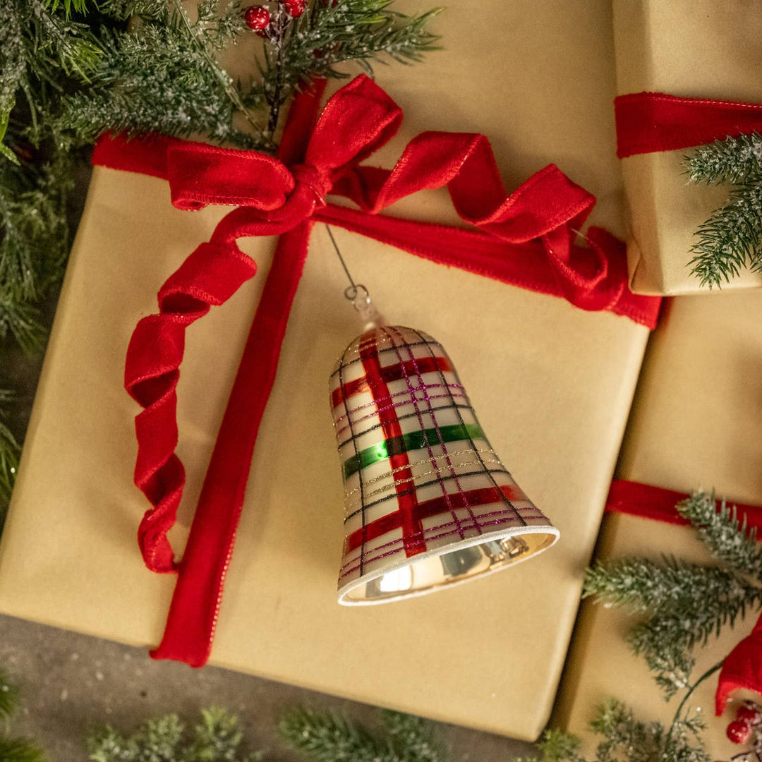 plaid glass bell christmas ornament with red green white pattern hanging on gift wrap